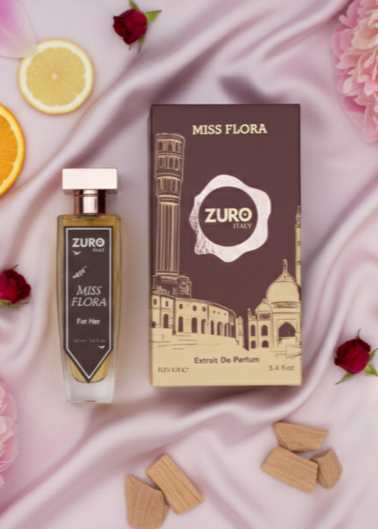 Zuro Miss Flora perfume bottle and packaging on a pink fabric background with flowers and oranges.
